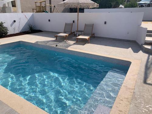 a swimming pool with two chairs and an umbrella at mangata suite home private pool in Spartokhórion