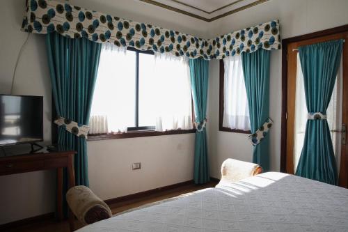 a bedroom with green curtains and a bed and a television at Hotel Boutique Vista Velero in Viña del Mar