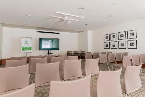 a room with white chairs and a projection screen at Holiday Inn Porto Gaia by IHG in Vila Nova de Gaia