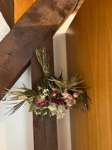 a flower arrangement on a wooden cross hanging on a wall at Home sweet home in La Bresse