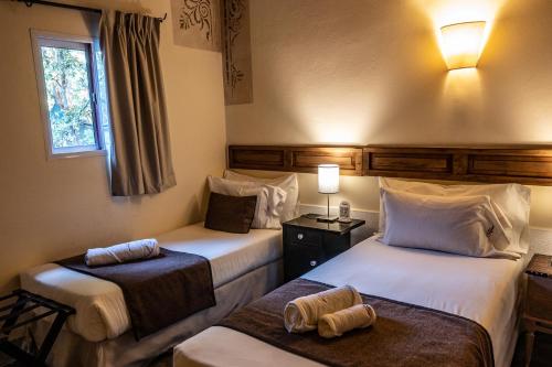 a hotel room with two beds and a window at Posada Borravino in Chacras de Coria