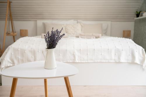a white vase on a table next to a bed at Szőlőhegy Vendégház Sümeg in Sümeg