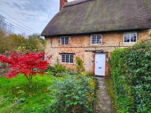 ein altes Backsteinhaus mit Strohdach in der Unterkunft Swan Cottage 2-Bedroom-Netflix-Parking-Nature-Canal in Kidlington