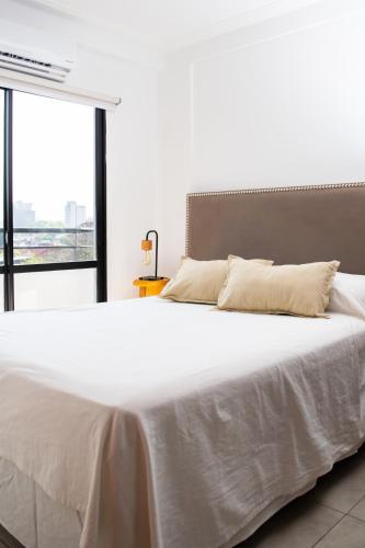a large white bed in a room with a window at Arrayanes 5 B in San Miguel de Tucumán