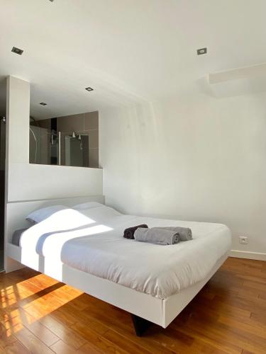 - une chambre blanche avec un grand lit blanc dans l'établissement L'Ecrin Meulière, à Conflans-Sainte-Honorine