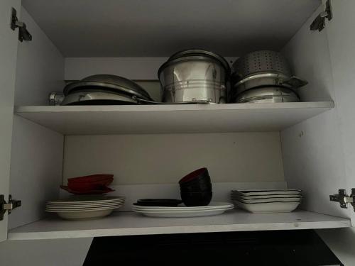 a shelf filled with plates and pans and bowls at Chill in Peace Staycation 2BR condo at Field Residences, Sucat near NAIA in Manila