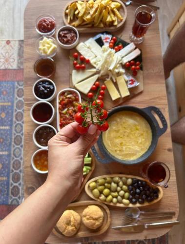 リゼにあるAurora Suit Bungalovの食べ物のテーブルの上にトマトの枝を持ち上げる人