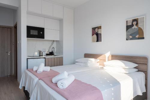 a white bedroom with a large bed with towels at Le Voyageur By the Sea - Furnished Rooms in Larnaka