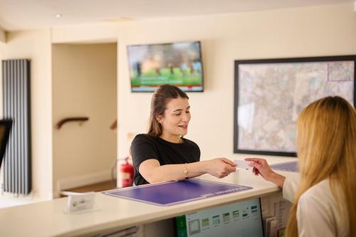 a woman standing at a counter talking to a woman at Discovery Inn - Leeds in Leeds