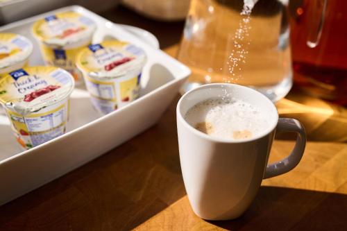 a cup of coffee sitting next to a tray of yogurt at Discovery Inn - Leeds in Leeds