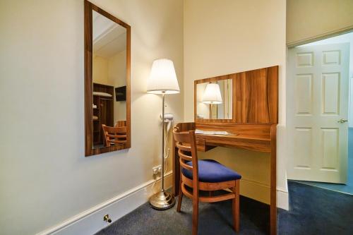a room with a desk with a lamp and a mirror at Discovery Inn - Leeds in Leeds