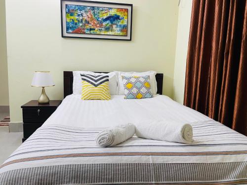 a bedroom with a large bed with white sheets and pillows at Citylights Bashundhara Chelsea Majestic Collection in Dhaka