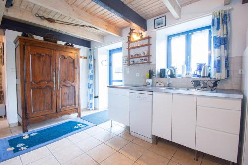 a kitchen with white cabinets and a wooden door at Le Gaoulac'H I Vue mer & Grand jardin in Crozon