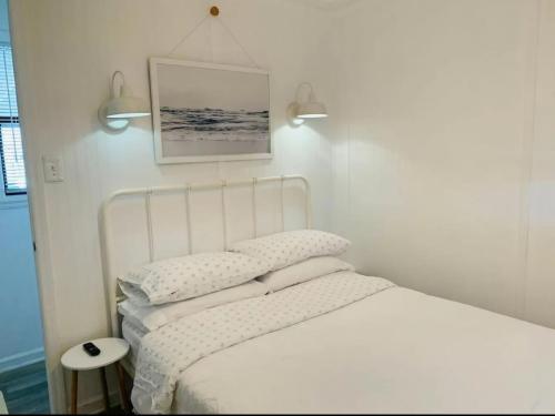 un letto con lenzuola e cuscini bianchi in una camera da letto di Just Add Water! a Secession