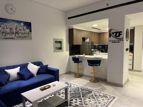 a living room with a blue couch and a kitchen at Jumeirah Heights in Dubai