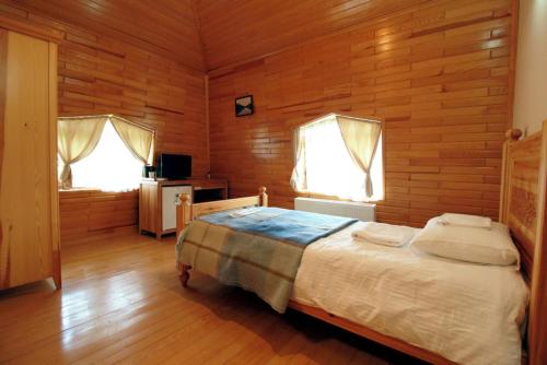 a bedroom with a bed and two windows at Lake Cildir Lodge in Çıldır