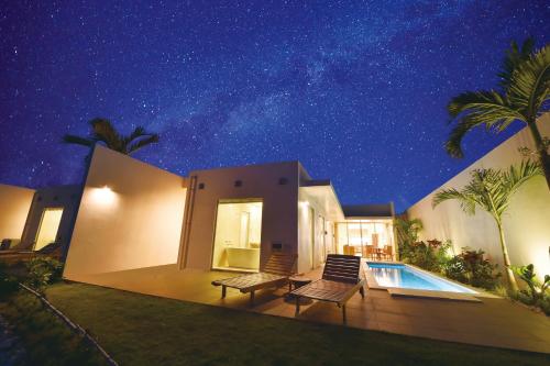 a house with a swimming pool at night at Feliz Villa Suite Miyakojima Ueno in Miyako Island