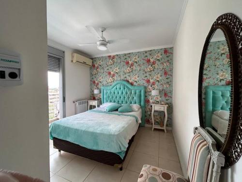 a bedroom with a blue bed and a mirror at Depto de lujo con cochera y piscina sobre Bv Gálvez in Vuelta del Paraguayo