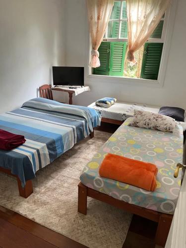 zwei Betten in einem Zimmer mit zwei Fenstern in der Unterkunft Pousada Inaya in Petrópolis