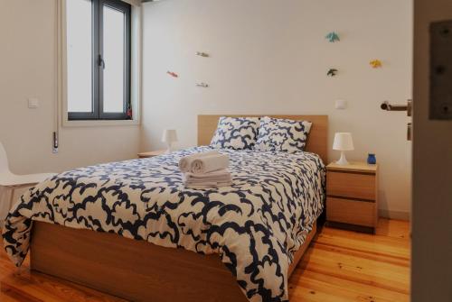 a bedroom with a bed with a black and white comforter at SpinBay Apartment in Espinho
