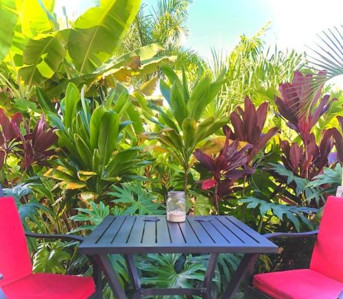 a blue table with two red chairs and a vase on it at Central Oceanview Modern Cozy 3 Bed House in Kailua-Kona
