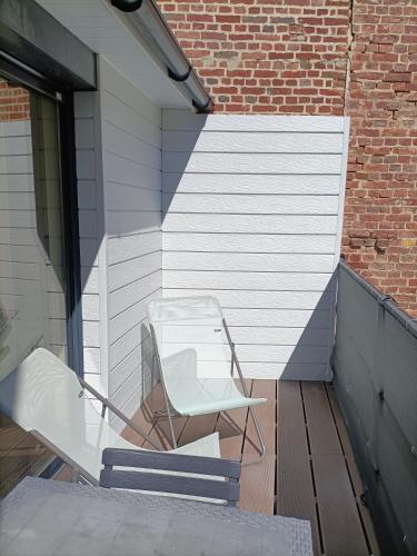 a white chair sitting on a porch next to a brick wall at SPA privatif à 50m de la plage - Studio in Mers-les-Bains