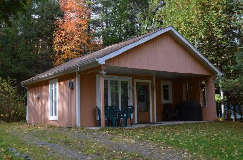 a small red cottage with a porch and chairs at Chalet Esmeralda in Piopolis