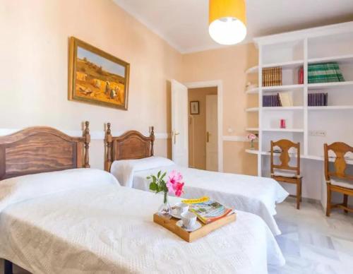 een slaapkamer met twee bedden en een tafel met bloemen bij Charming house in Arcos with private pool in Arcos de la Frontera