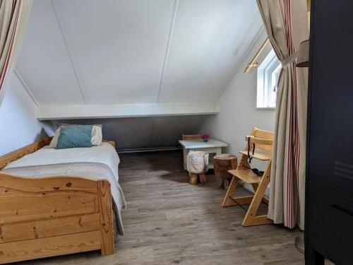 Un pequeño dormitorio con una cama y una mesa. en Spacious Bungalow near Water, en Breskens