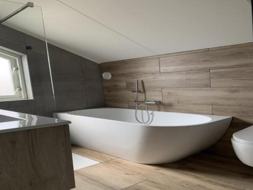 Un baño con bañera blanca y un inodoro. en Spacious Bungalow near Water, en Breskens
