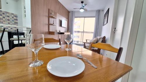una mesa de madera con dos platos y vasos. en Apto moderno com varanda, piscina e academia, en Río de Janeiro