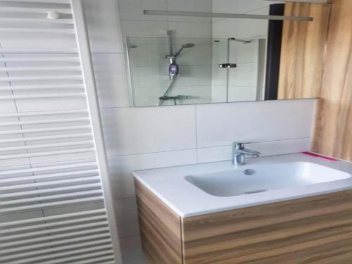 Un baño blanco con lavabo y espejo. en Bungalow in Breskens near Beach and Dunes, en Breskens