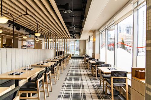 a restaurant with wooden tables and chairs and windows at Delta Hotels by Marriott Ottawa City Centre in Ottawa