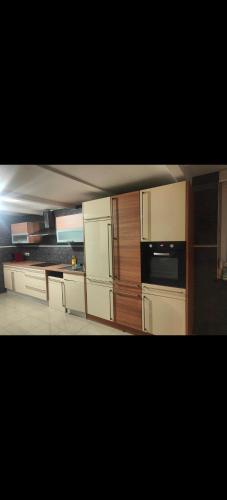 une cuisine avec des armoires blanches et un four à plaques de cuisson dans l'établissement Auberge du manala chambre 4 personnes 24-24, à Saint-Louis