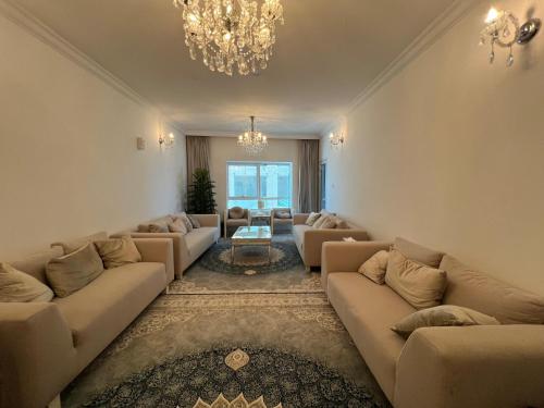 a living room with couches and a chandelier at The Family Spot in Sharjah