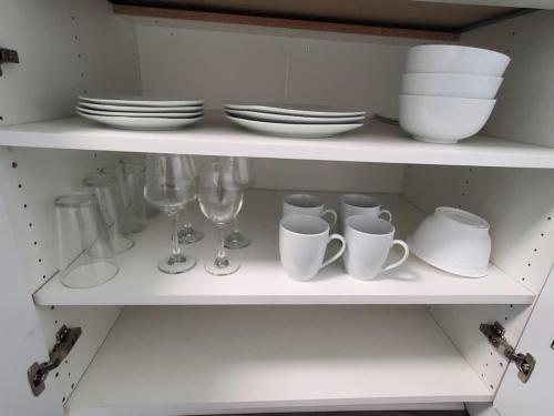a white shelf with dishes and glasses and plates at Parking Netflix Near Airport in Thunder Bay