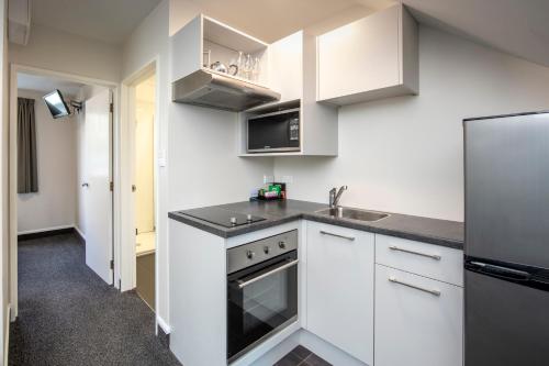a kitchen with white cabinets and a stainless steel refrigerator at Ashford Motor Lodge in Christchurch