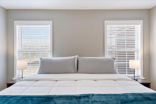 a bedroom with a large bed with two windows at Beautiful 3 bed 2 bath home near Crystal Bridges in Bentonville