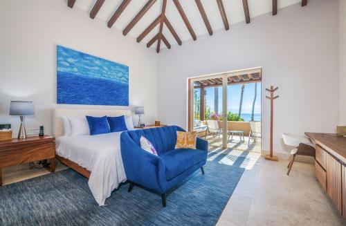 Un dormitorio con una cama y una silla azul. en Beachfront Enchanting Villa in Punta Mita, en Punta Mita