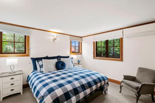 a bedroom with a bed and a chair and windows at Kew Cottage in Greytown
