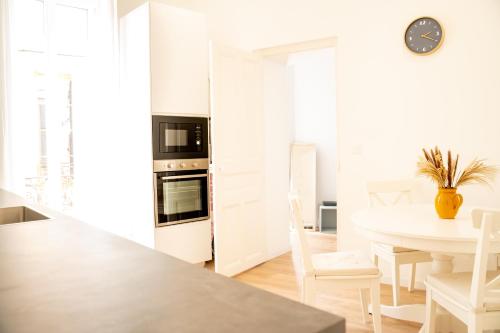 une cuisine blanche avec une table et une salle à manger dans l'établissement L'atelier de la Placette YourHostHelper, à Nîmes