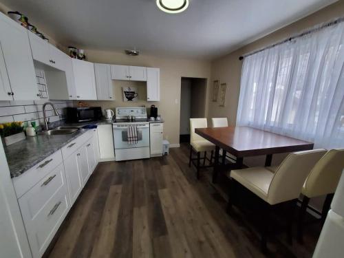 a kitchen with white cabinets and a wooden table at Cozy Home with Whole main floor in Thunder Bay