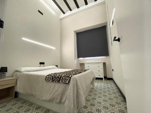 a white bedroom with a bed and a large screen at Apartamento Plaza del Cabildo II - Sanlúcar Centro in Sanlúcar de Barrameda