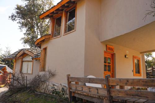 a house with a wooden bench in front of it at Lelikelen Cabañas del Bosque in Villa La Angostura
