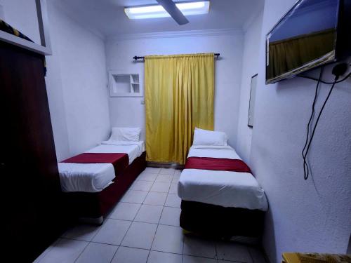 a room with two beds and a yellow curtain at فندق النجمتين الفضية in An Naqāʼ