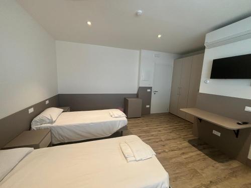a room with two beds and a flat screen tv at Affittacamere Cossetti in Pordenone