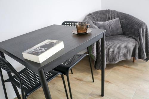 a table and chair with a book and a cup on it at Sosnówka Pokoje Gościnne in Borne Sulinowo