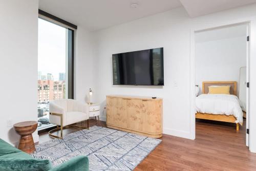 a white room with a bed and a television at Back-Bay 2BR Condo w Roof top Gym Parking in Boston