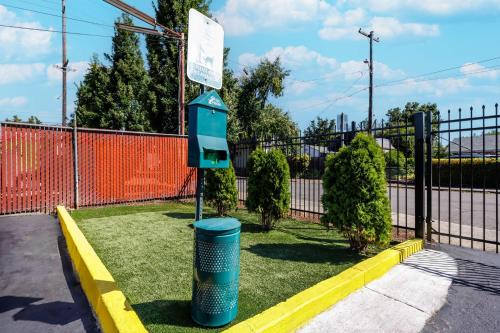 a blue trash can sitting in the grass next to a fence at Motel 6 Portland OR Southeast in Portland