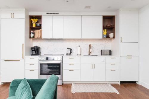 a kitchen with white cabinets and a green couch at Back-Bay 2BR Condo w Roof top Gym Parking in Boston